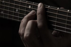 A man pressing the guitar chord