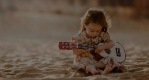 Girl playing Ukulele on the sands